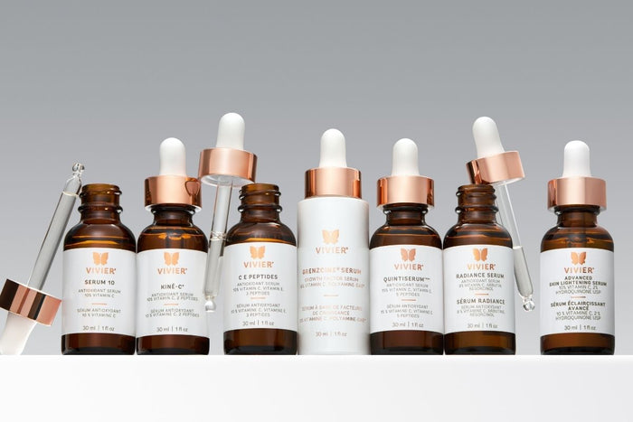 Collection of Vivier skincare serums in amber glass bottles with rose gold droppers displayed side by side.