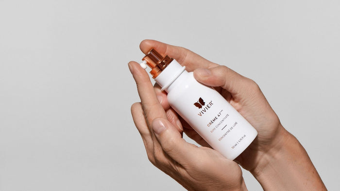 Mains tenant une bouteille de Crème 47 Luxe Concentré de Vivier avec de l'hydratant sortant de la pompe.