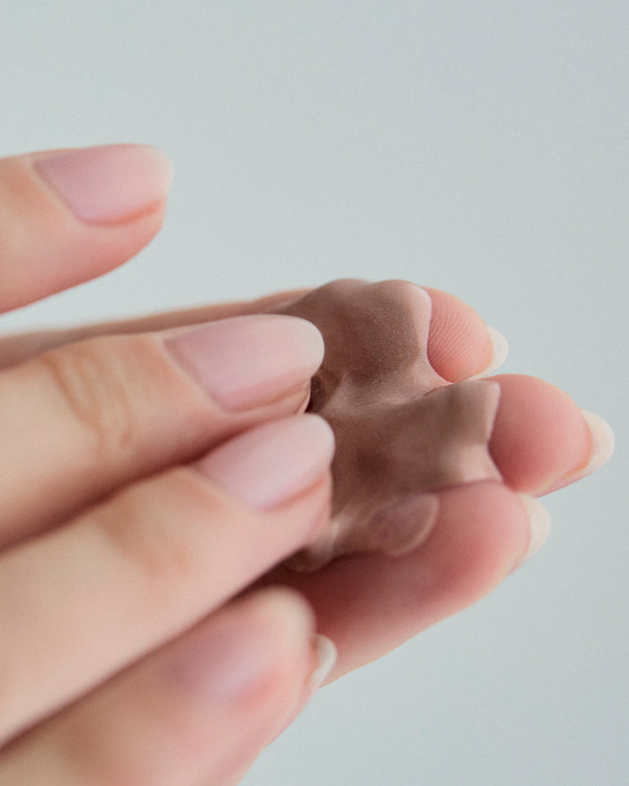 Close-up of a person holding a small amount of rich, creamy sunscreen between their fingertips.